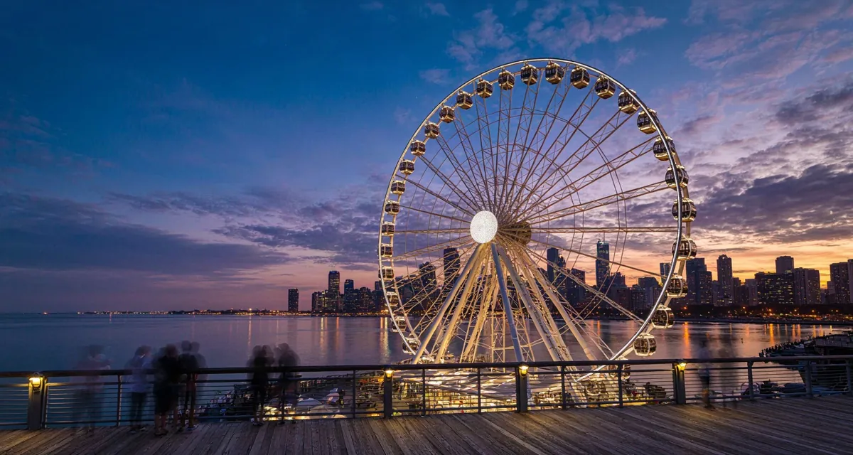 La rueda de Chicago en Chicago (Centennial Wheel) iluminada al atardecer en Navy Pier, con sus góndolas cerradas y el skyline de la ciudad reflejado en el lago Michigan